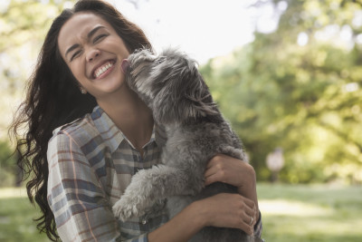 Mixed race woman playing with dog in park